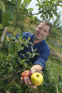 Dr. John Cline in orchard holding apples