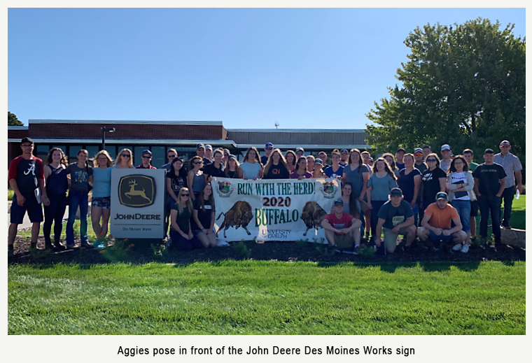 Aggies pose in front of the John Deere Des Moines Works sign 